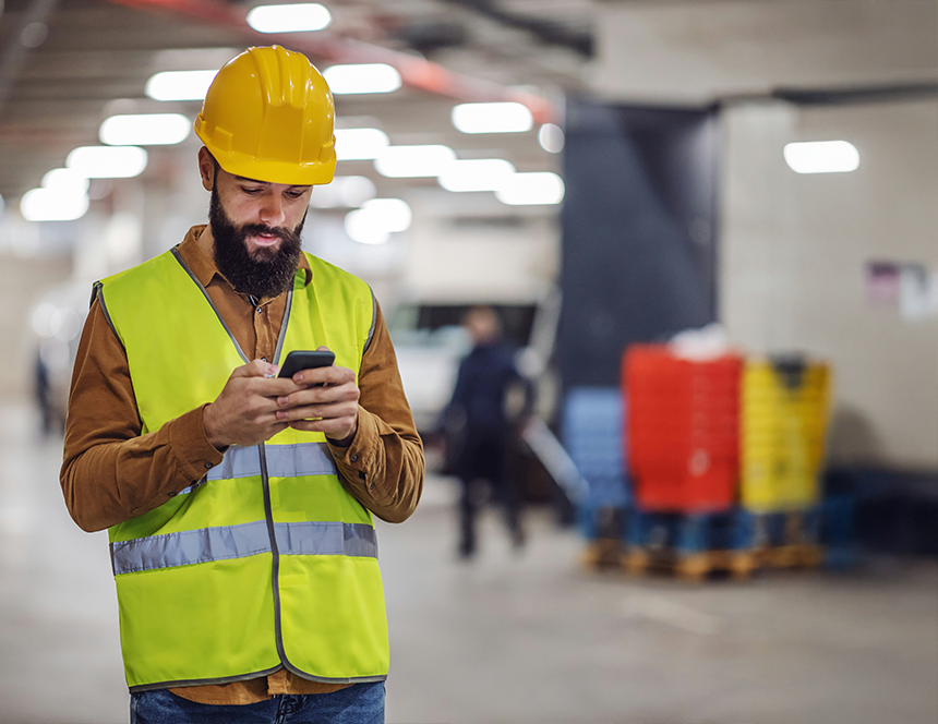 Person wearing high vis and hard hat, checking phone